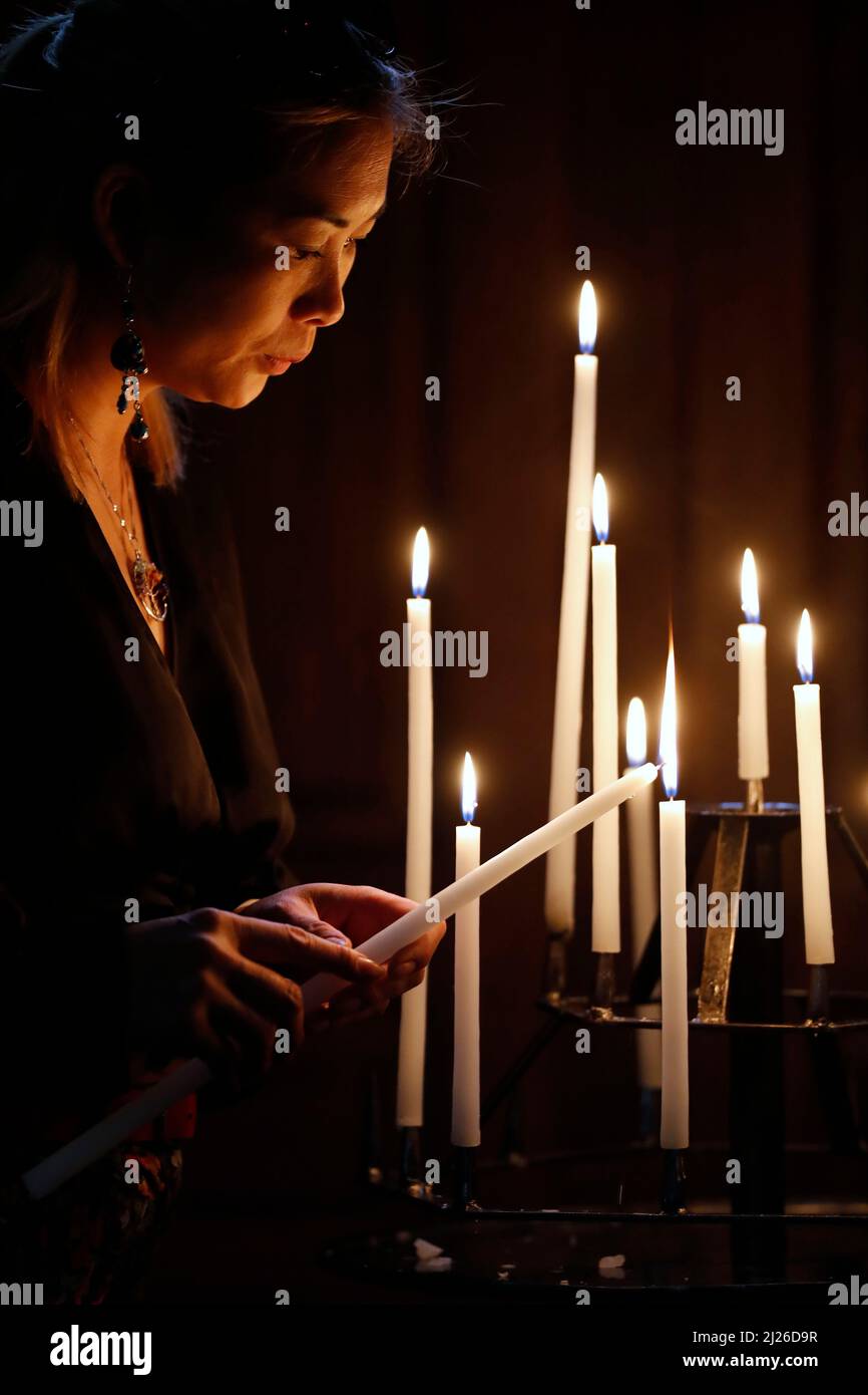Katholische Frau, die in einer Kirche mit Kerzen betet. Kirche Kerzen in der Kirche. Frau, die die Jungfrau betet. Stockfoto