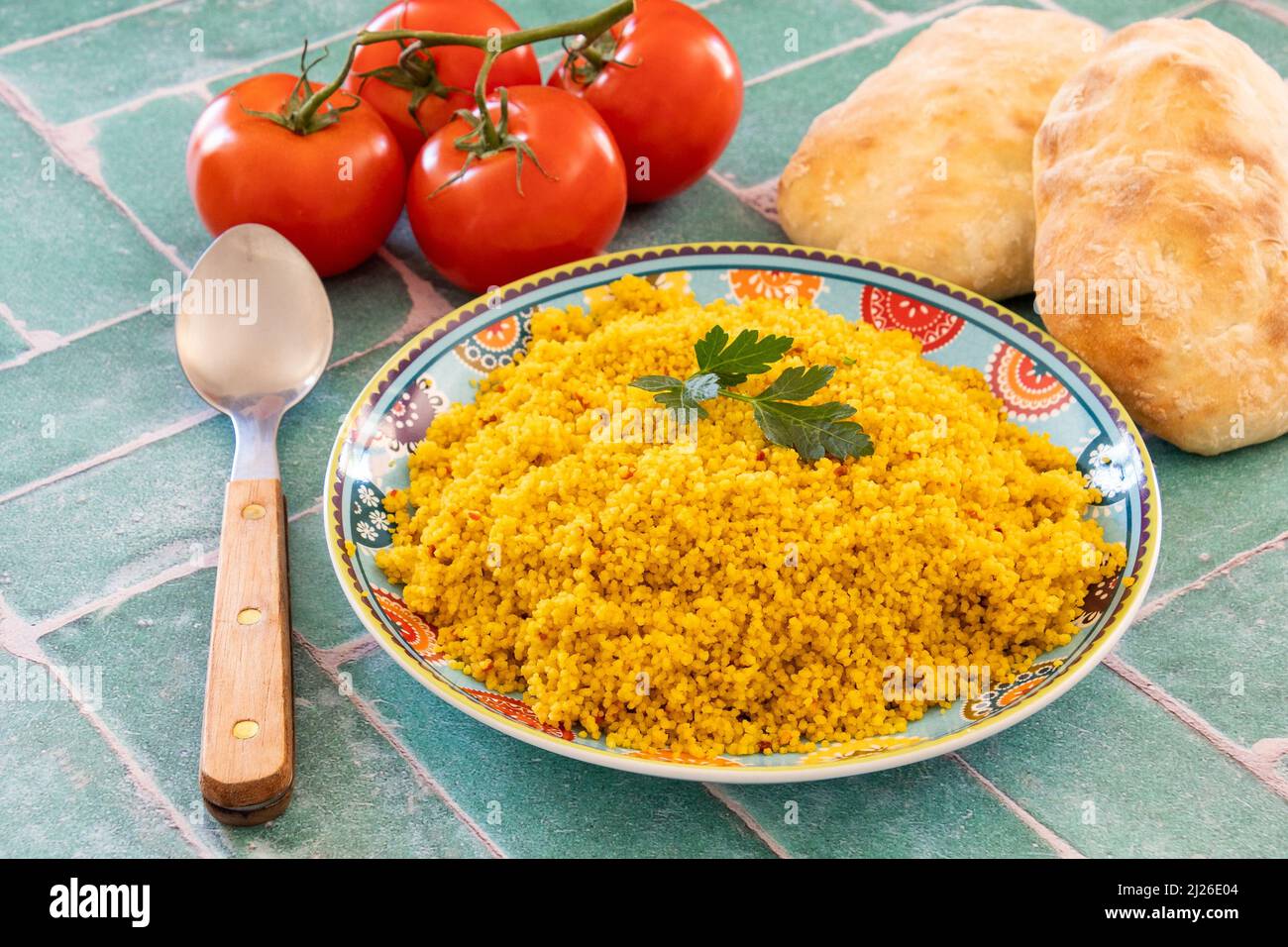 Draufsicht auf Tabbouleh-Gericht, reife Tomaten und Brot auf einem Tisch Stockfoto