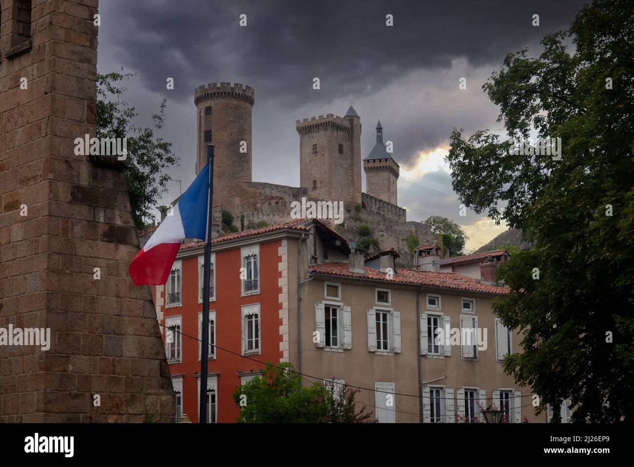 Blick auf die mittelalterlichen Burgtürme und die französische Flagge in der Stadt Foix, der Hauptstadt des Départements Ariège im Südwesten Frankreichs Stockfoto