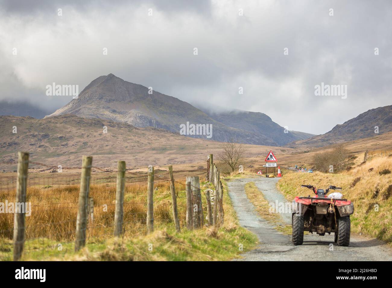 Isoliertes Quad-Bike auf der Feldweg unter dem Berg Snowdon in Nordwales, Großbritannien. Straßenbauzeichen auf der Hauptstraße, Route durch den Snowdonia Nationalpark. Stockfoto