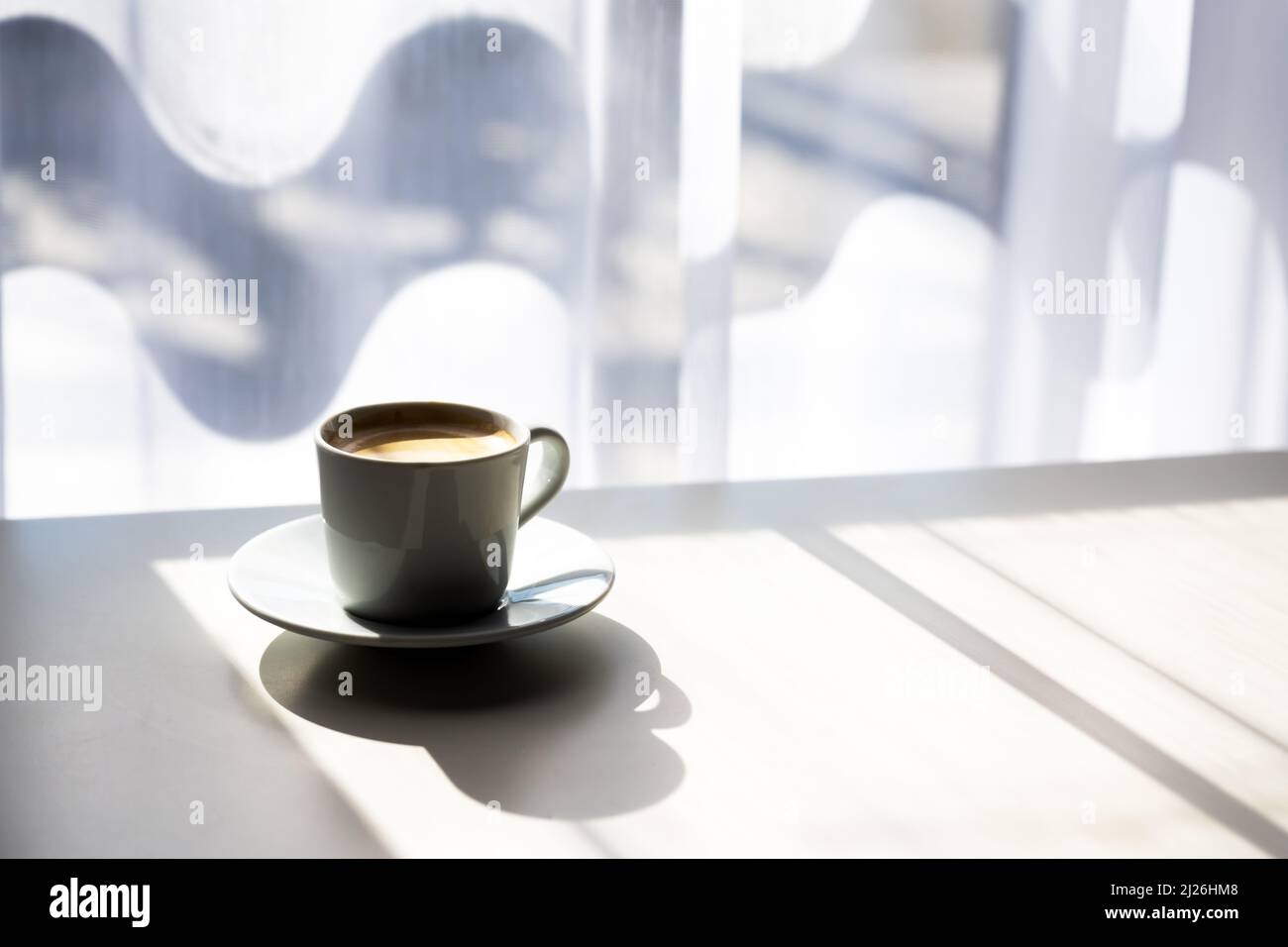 Espresso-Kaffeetasse auf dem Tisch in der Nähe des Fensters mit Morgenlicht. Fotos von Speisen und Getränken Stockfoto
