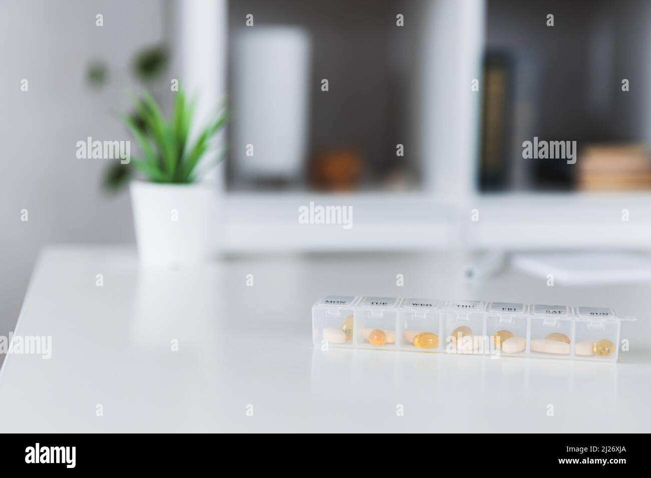 Nahaufnahme der medizinischen Pille Box mit Dosen von Tabletten für den täglichen Nehmen Sie ein Medikament mit weißen, gelben Drogen und Kapseln zur Behandlung verwendet, die Krankheit zu heilen. Gesunder Lebensstil, Vitamine, Omega-3-Ergänzungen Stockfoto