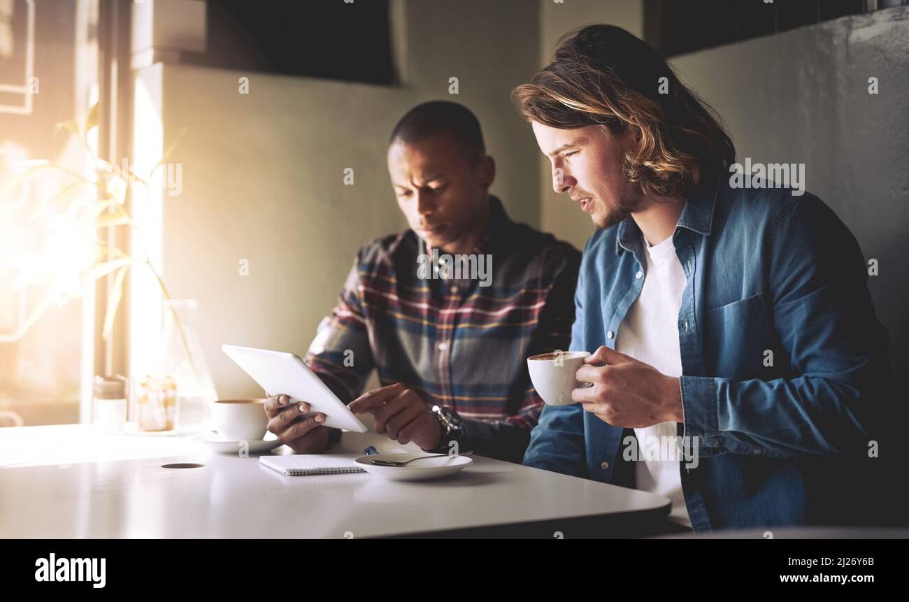 Das sieht nicht gut aus. Aufnahme von zwei Freunden, die ein Tablet benutzen, während sie in einem Café Kaffee trinken. Stockfoto