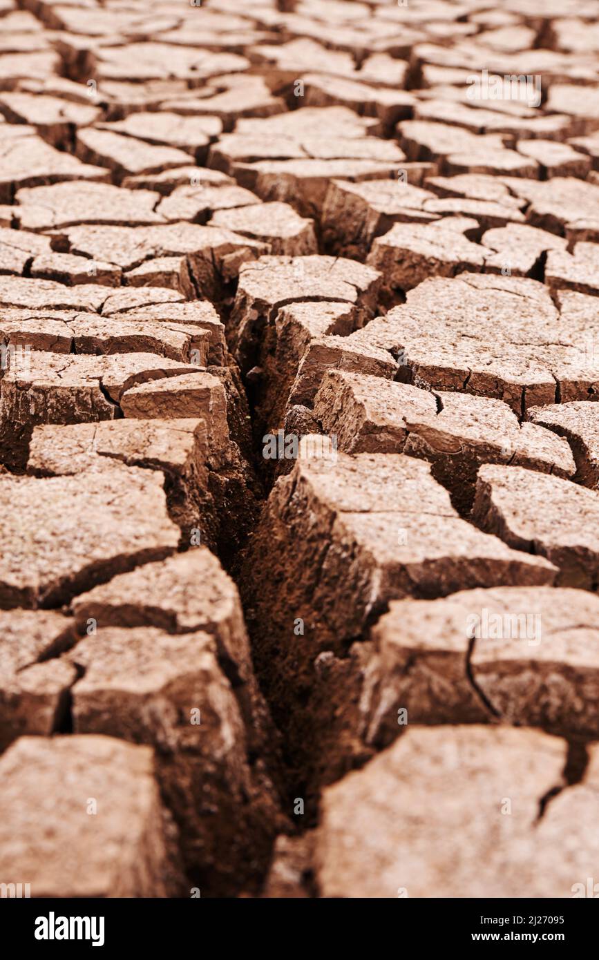 Von der Sommerhitze geknackt. Trockener rissiger Boden in der afrikanischen Landschaft. Stockfoto