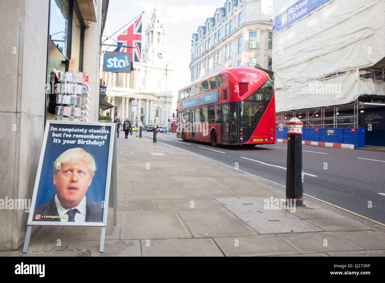 Ein Doppeldeckerbus fährt an einem Schild mit dem britischen Premierminister Boris Johnson vorbei, das vor einem Grusskarten-Laden im Zentrum von London zu sehen ist. Stockfoto