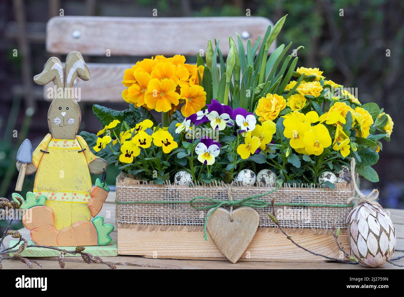 osterdekoration mit gelben Viola-Blüten und Primeln in Holzkiste und osterhase Stockfoto