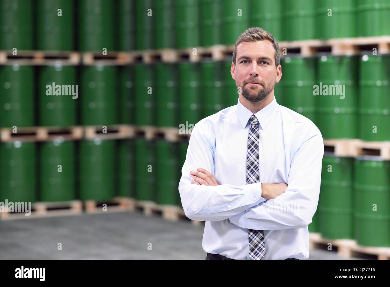 Porträt eines Managers in einem Logistik Unternehmen - im Hintergrund ein Lager mit Chemikalien und waren einer chemischen Fabrik Stockfoto