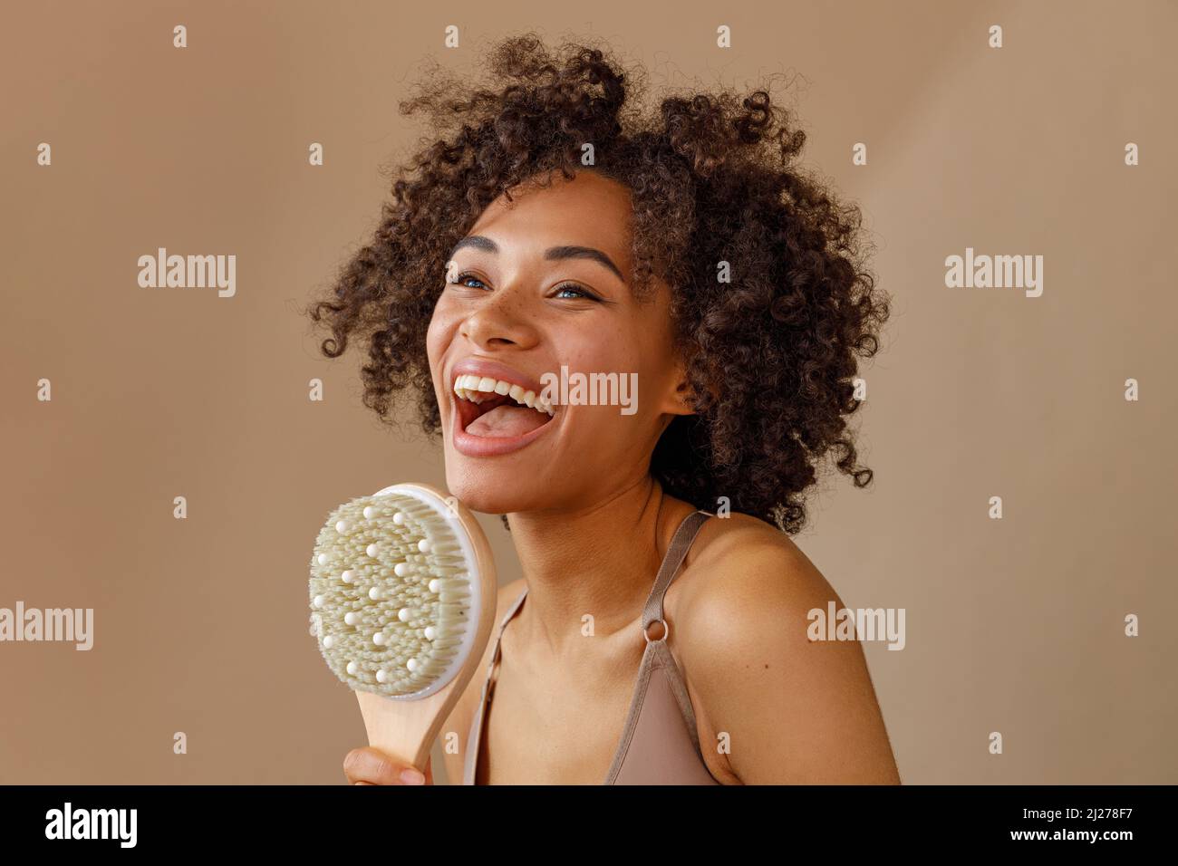 Glückliche Dame, die Massage-Bürste im Studio darstellt Stockfoto