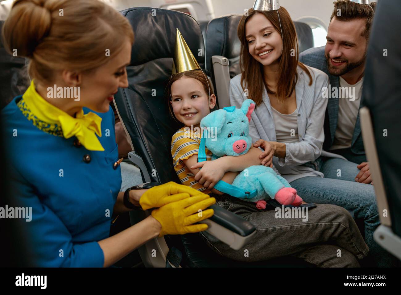 Familie feiert Kindergeburtstag und spricht mit Stewardess im Flugzeug Stockfoto