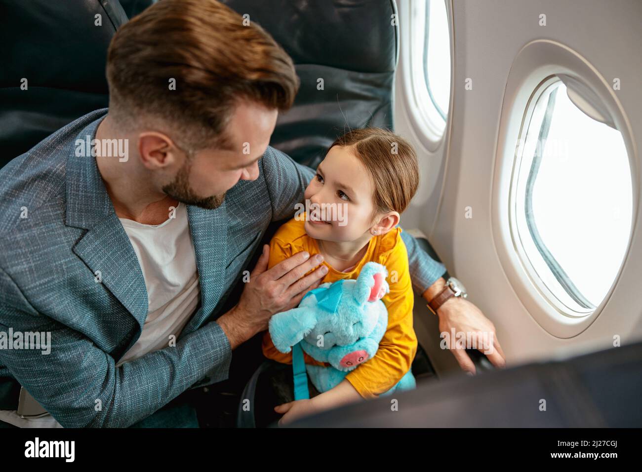 Mann mit Tochter sitzt am Fenster im Flugzeug Stockfoto