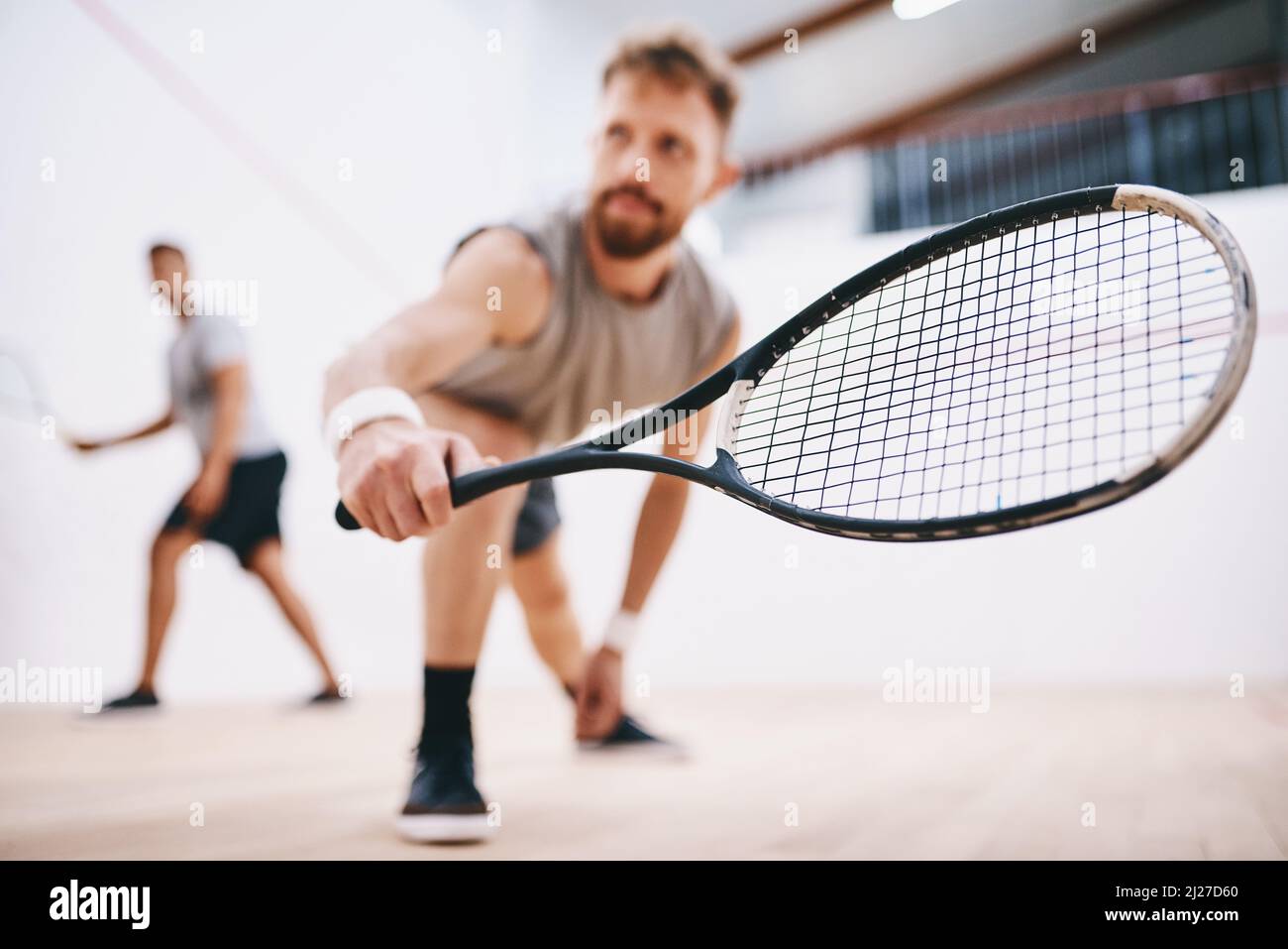 Nehmen Sie Ihre Augen nicht eine Sekunde lang vom Ball. Aufnahme von zwei jungen Männern, die ein Squash-Spiel spielen. Stockfoto