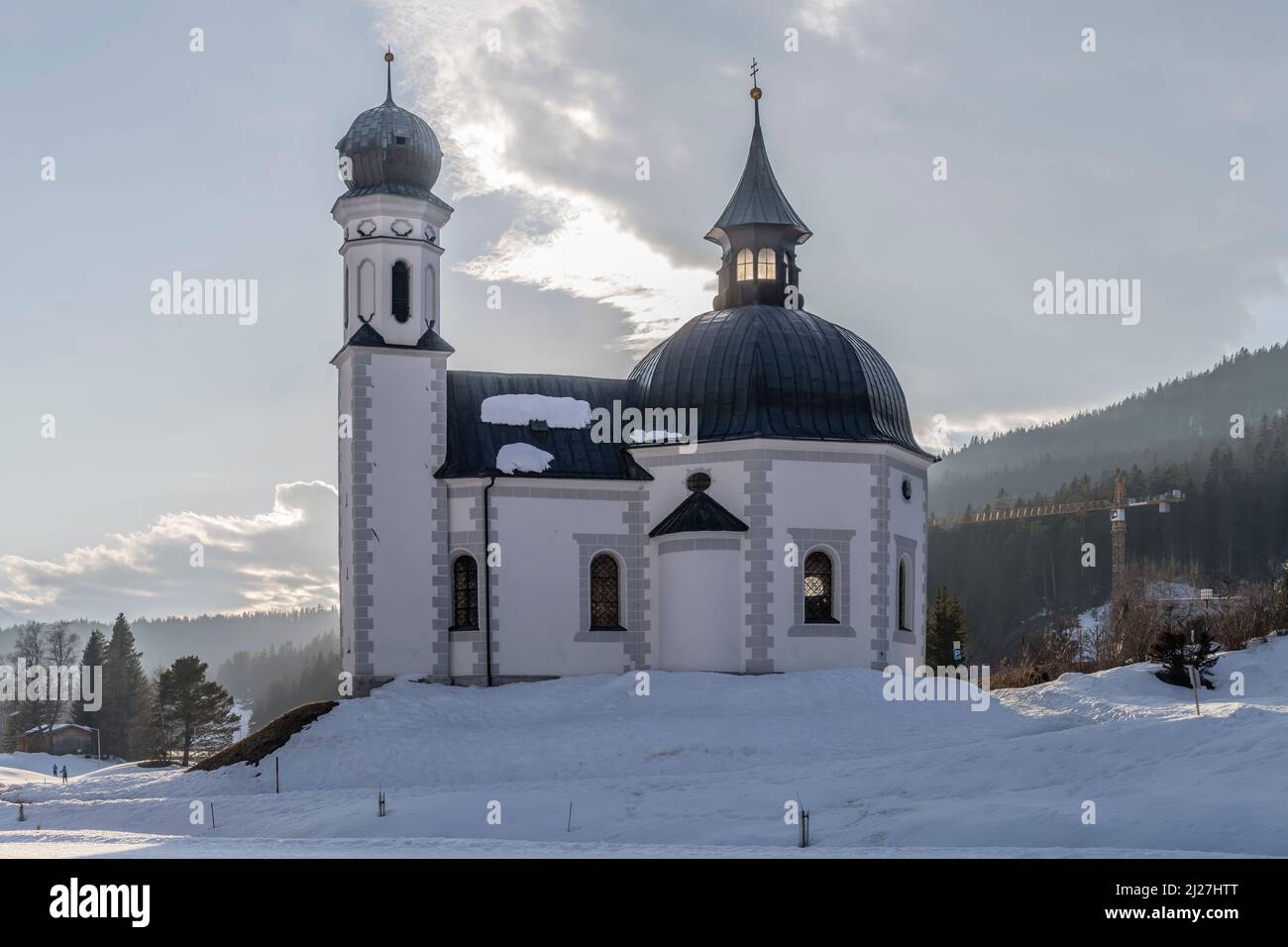 Stadtbild mit pittoresker barocker Seekirchl-Kirche auf schneebedecktem Boden in touristischer Volllage, aufgenommen im hellen Winterlicht bei Seefeld, Tirol Stockfoto