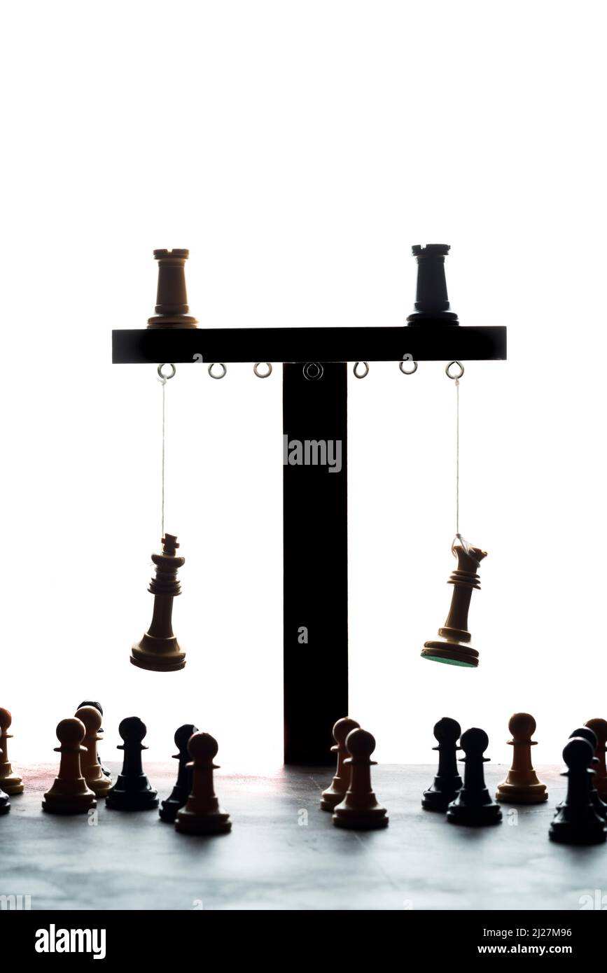 Schachkönig und -Königin hängen an einem simulierten Galgen, umgeben von Bauern. Konzeptfoto, das die Hinrichtung der herrschenden Klasse durch den Peop zeigt Stockfoto