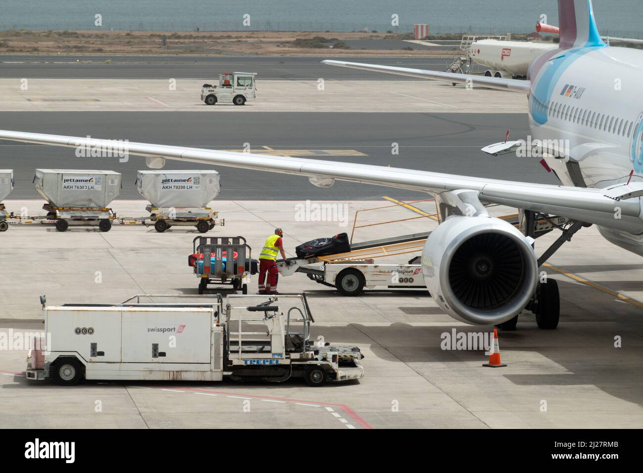 Ein Gepäckhandler, der für Swissport arbeitet, verlädt Passagierkoffer und Gepäck auf ein Flugzeug, das für den Start auf einer Start- und Landebahn des Flughafens vorbereitet ist. Stockfoto