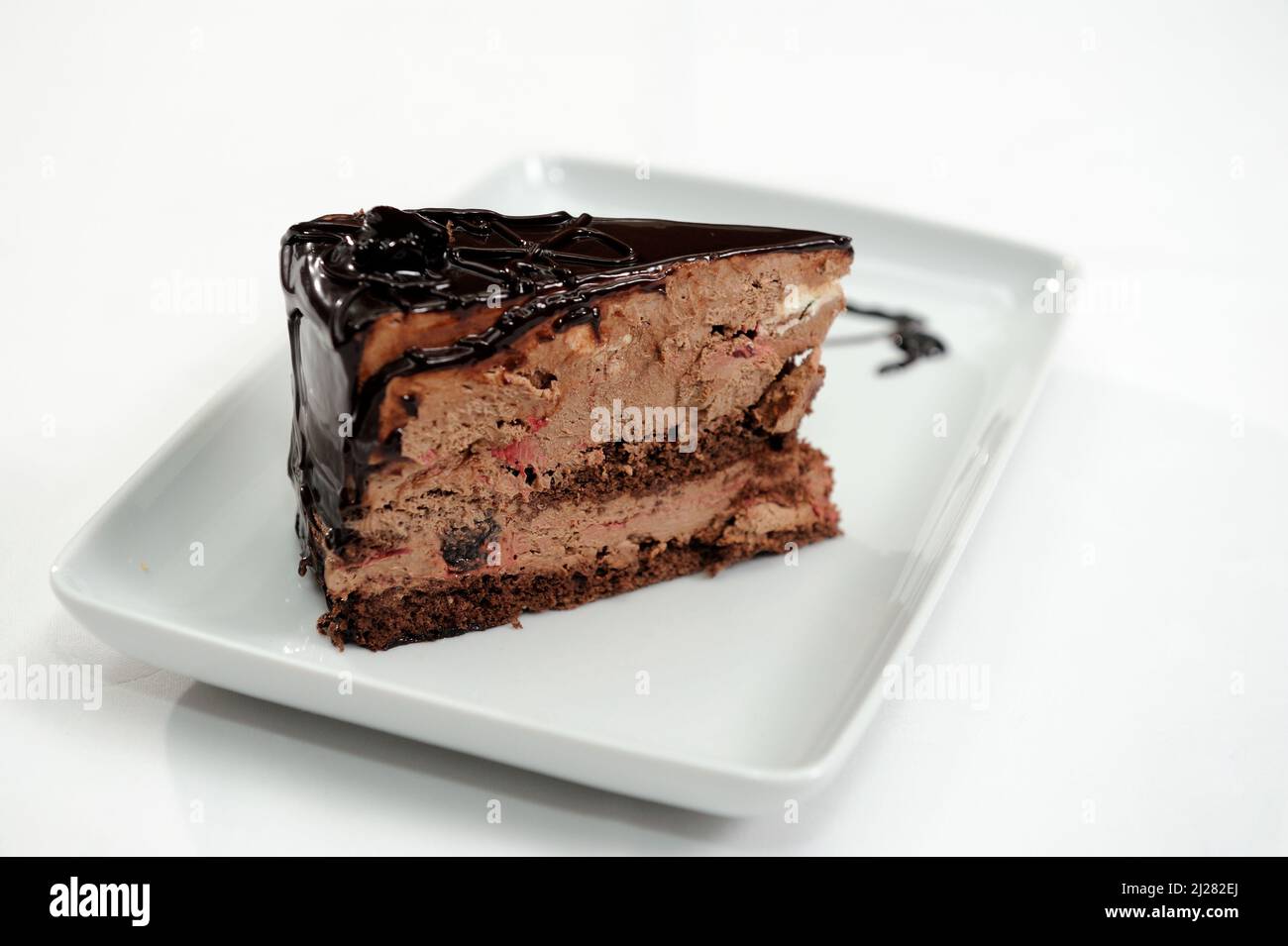 Nahaufnahme eines Stücks Schokoladenkuchen mit Schokoladenmousse auf einem weißen Teller Stockfoto