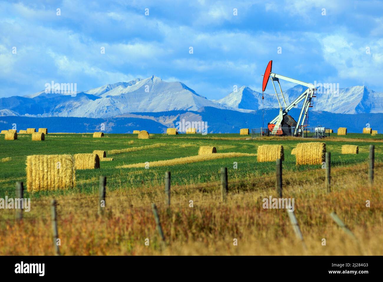Ein Pumpjack-Bohrgerät der Öl- und Gasindustrie in den kanadischen Prärien mit den kanadischen Rockies in Alberta, Kanada. Stockfoto