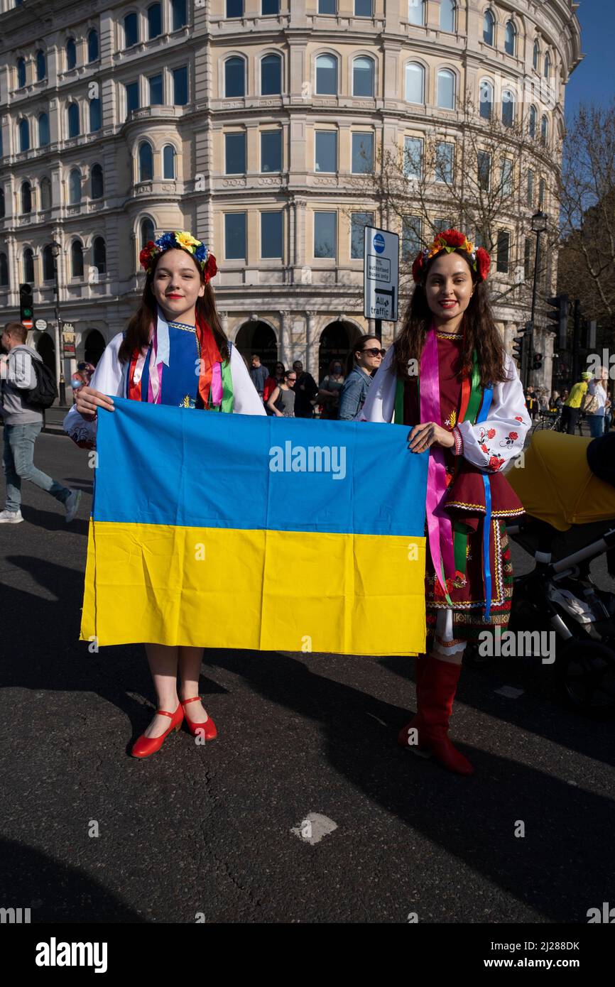 Junge Frauen mit traditionellen Blumen im Haar treffen sich am 26.. März 2022 in London, Großbritannien, zu einem friedensmarsch ‘London steht mit der Ukraine’ in der Hauptstadt. Der Konflikt in der Ukraine befindet sich nun in seinem zweiten Monat, und ihr Präsident hat die Menschen auf der ganzen Welt dazu aufgerufen, sich gegen die russische Invasion und den anhaltenden Krieg in der Region zu vereinen. Die ukrainische Flagge in Gelb und Blau war überall in dieser bunten Show der Einheit zu sehen. Stockfoto