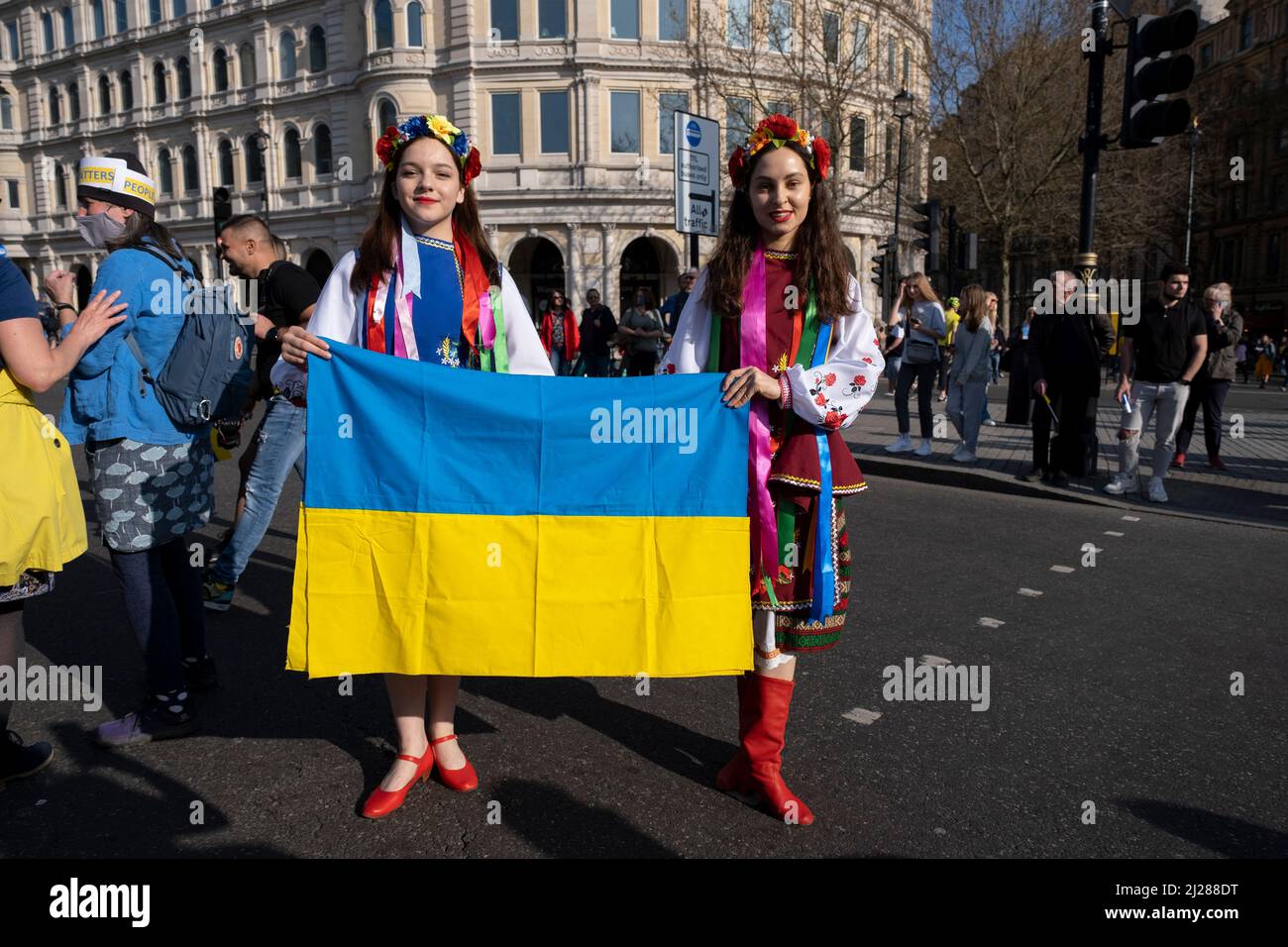 Junge Frauen mit traditionellen Blumen im Haar treffen sich am 26.. März 2022 in London, Großbritannien, zu einem friedensmarsch ‘London steht mit der Ukraine’ in der Hauptstadt. Der Konflikt in der Ukraine befindet sich nun in seinem zweiten Monat, und ihr Präsident hat die Menschen auf der ganzen Welt dazu aufgerufen, sich gegen die russische Invasion und den anhaltenden Krieg in der Region zu vereinen. Die ukrainische Flagge in Gelb und Blau war überall in dieser bunten Show der Einheit zu sehen. Stockfoto