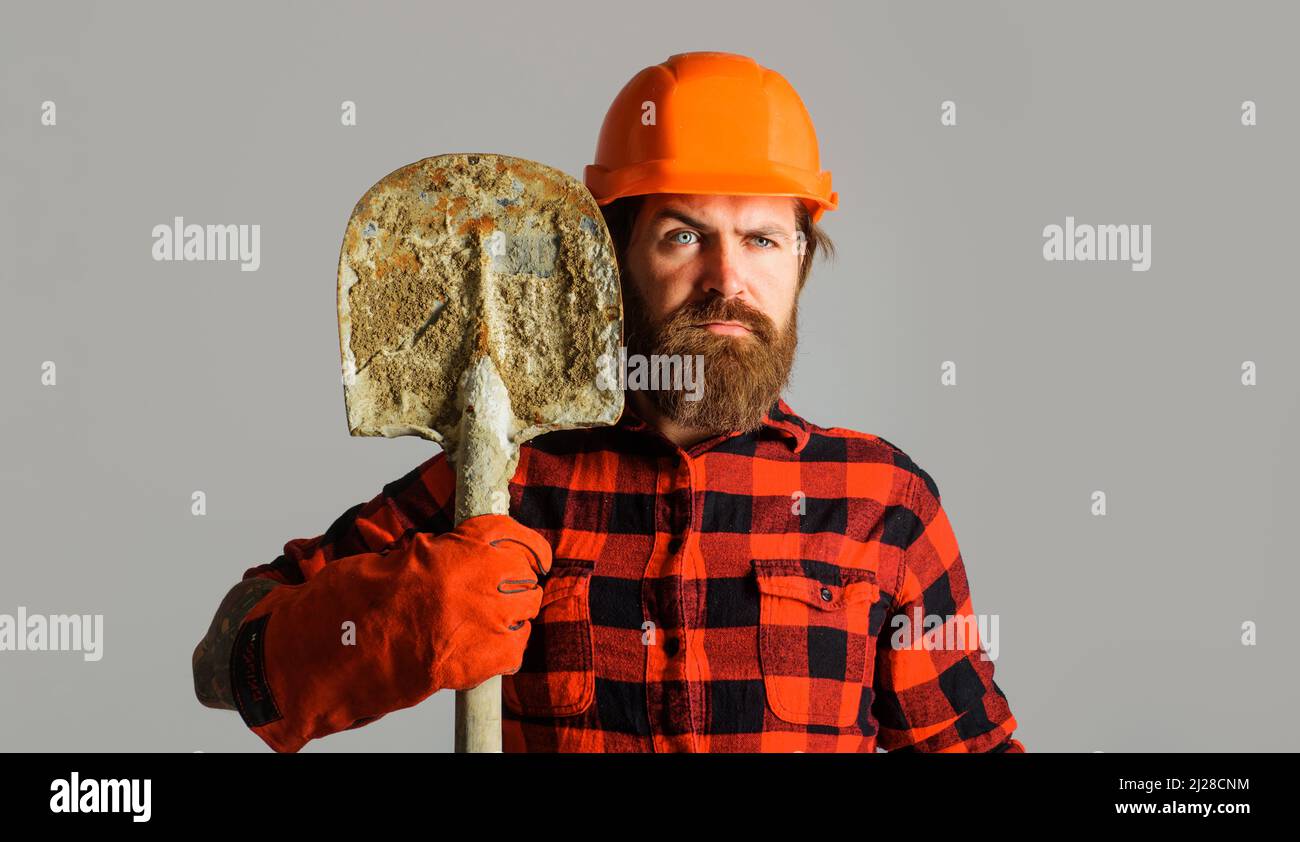 Bauarbeiter in Harthut mit Schaufel. Baumeister oder Arbeiter in Arbeitshandschuhen mit Spaten. Stockfoto