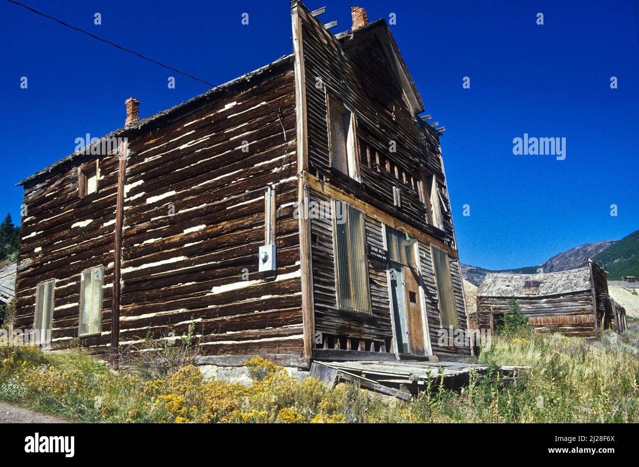 MT: Jefferson County, Boulder Valley, Elkhorn (Geisterstadt), verlassene Holzhandlung mit falscher Fassade, vor der ein Gehweg aus Holz auf einer Straße überlebte Stockfoto