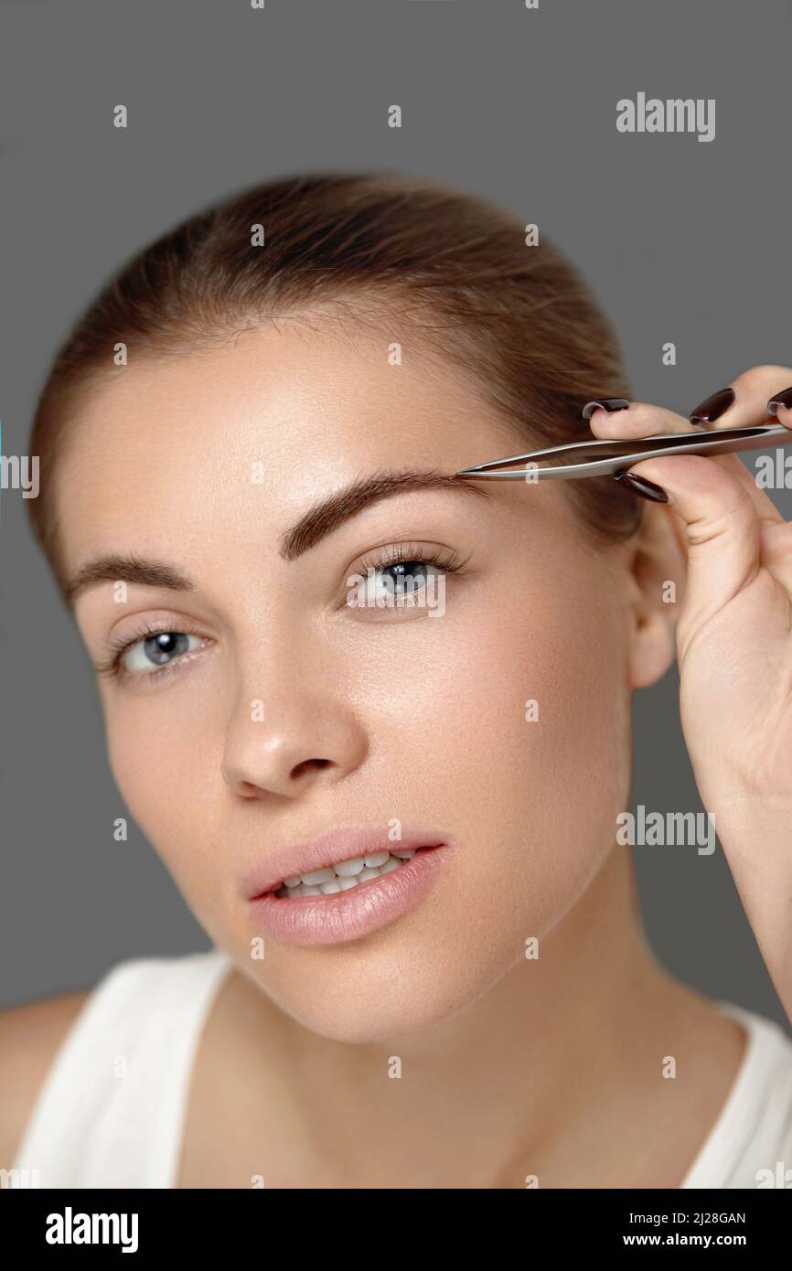 Augenbrauenkorrektur. Schöne junge Frau pinkiert Augenbrauen. Modell mit Schönheit Gesicht Zupfen Augenbrauen. Stockfoto