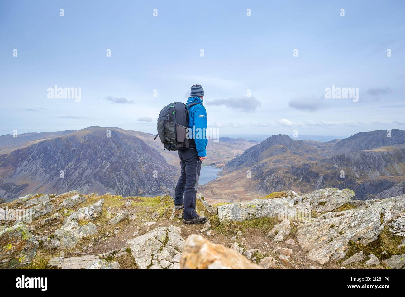 Rückansicht eines isolierten Wanderers mit Rucksack, der Anfang des Frühlings in den Bergen des Snowdonia National Park, North Wales, Großbritannien, unterwegs war. Stockfoto