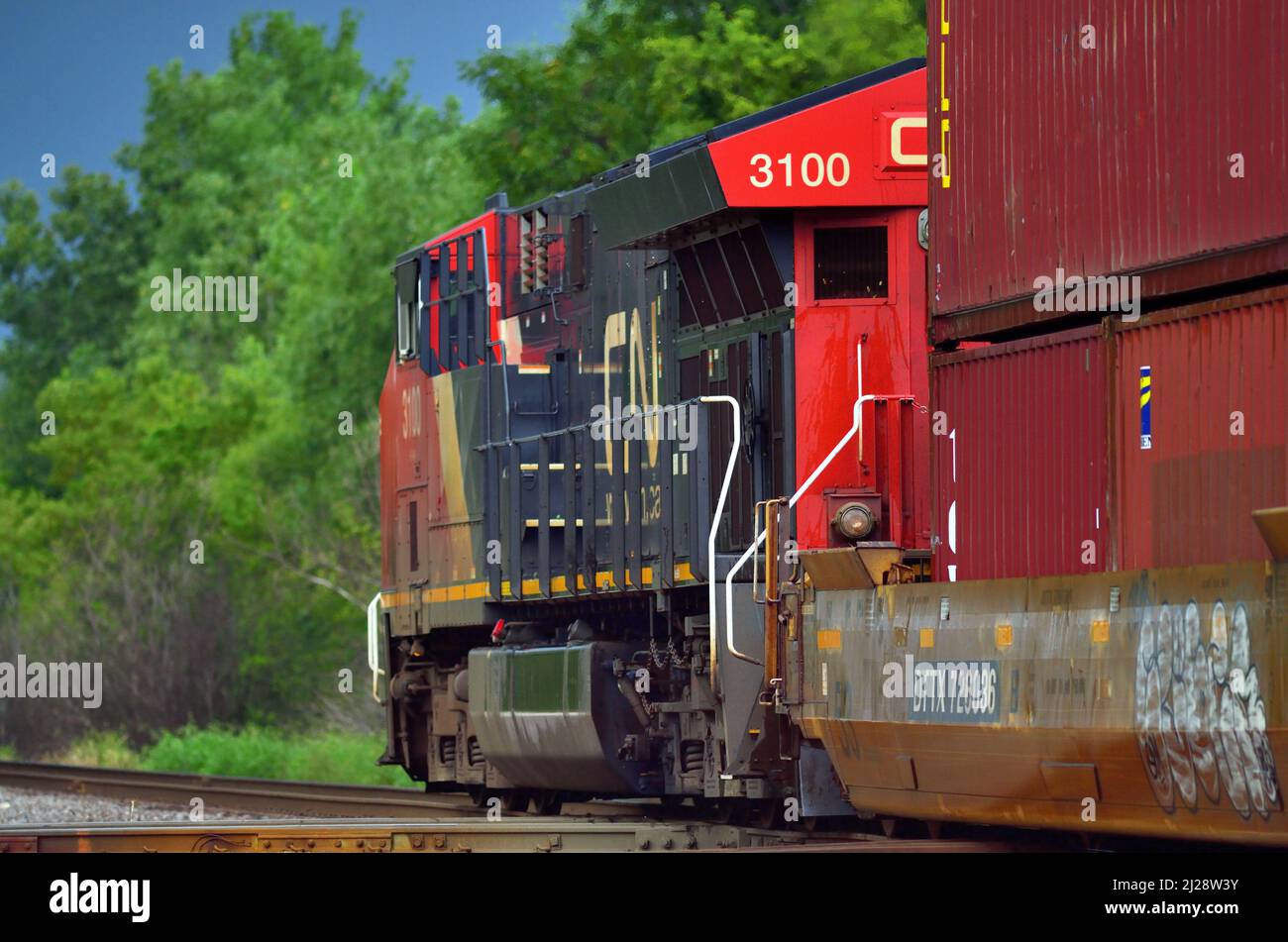 Elgin, Illinois, USA. Die Sonne scheint auf einem intermodalen Güterzug der Canadian National Railway, der von einer einzigen Lokomotive angetrieben wird. Stockfoto