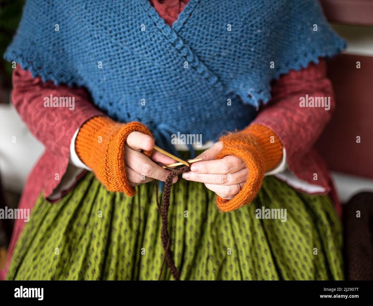 Frau strickt, während sie Kleidung aus der Mitte des 19.. Jahrhunderts im Fort Nisqualy Living History Museum trägt Stockfoto