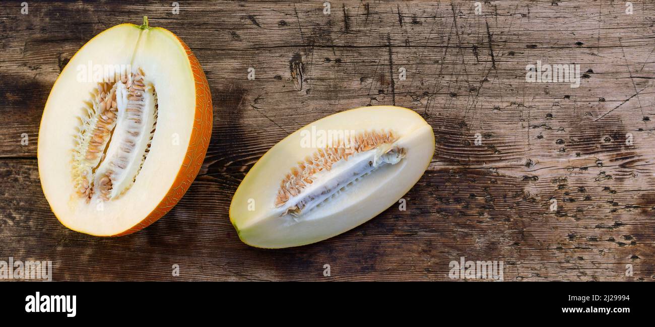 Anderthalb Viertel einer Melone im Schnitt auf einem hölzernen Hintergrund. Stockfoto