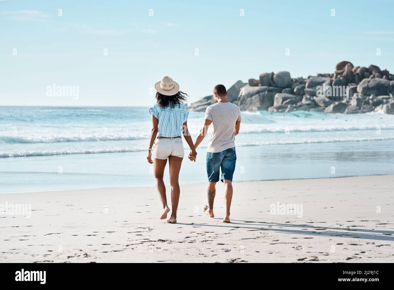 Liebe Ebbe und Flut wie die Gezeiten. Rückansicht eines jungen Paares, das am Strand entlang läuft. Stockfoto