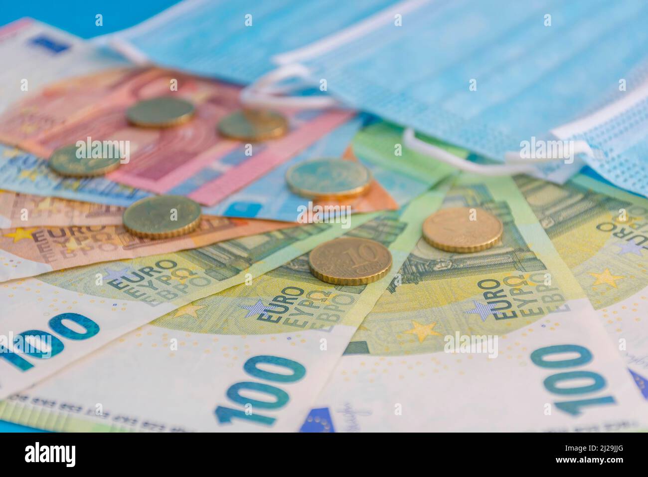 Medizinische Masken und Euro-Banknoten. Finanzkrise aufgrund von Coronavirus-Verlusten, selektiver Fokus Stockfoto