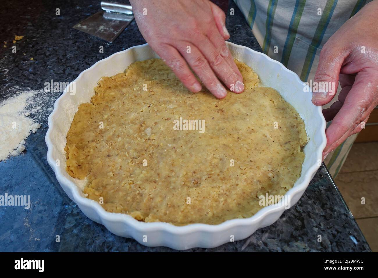 Süddeutsche Küche, Backen, herzhafte Gemüsetorte mit Walnussbasis zubereiten, Walnussteig in die Backform pressen, Tortenform, Quiche-Form Stockfoto