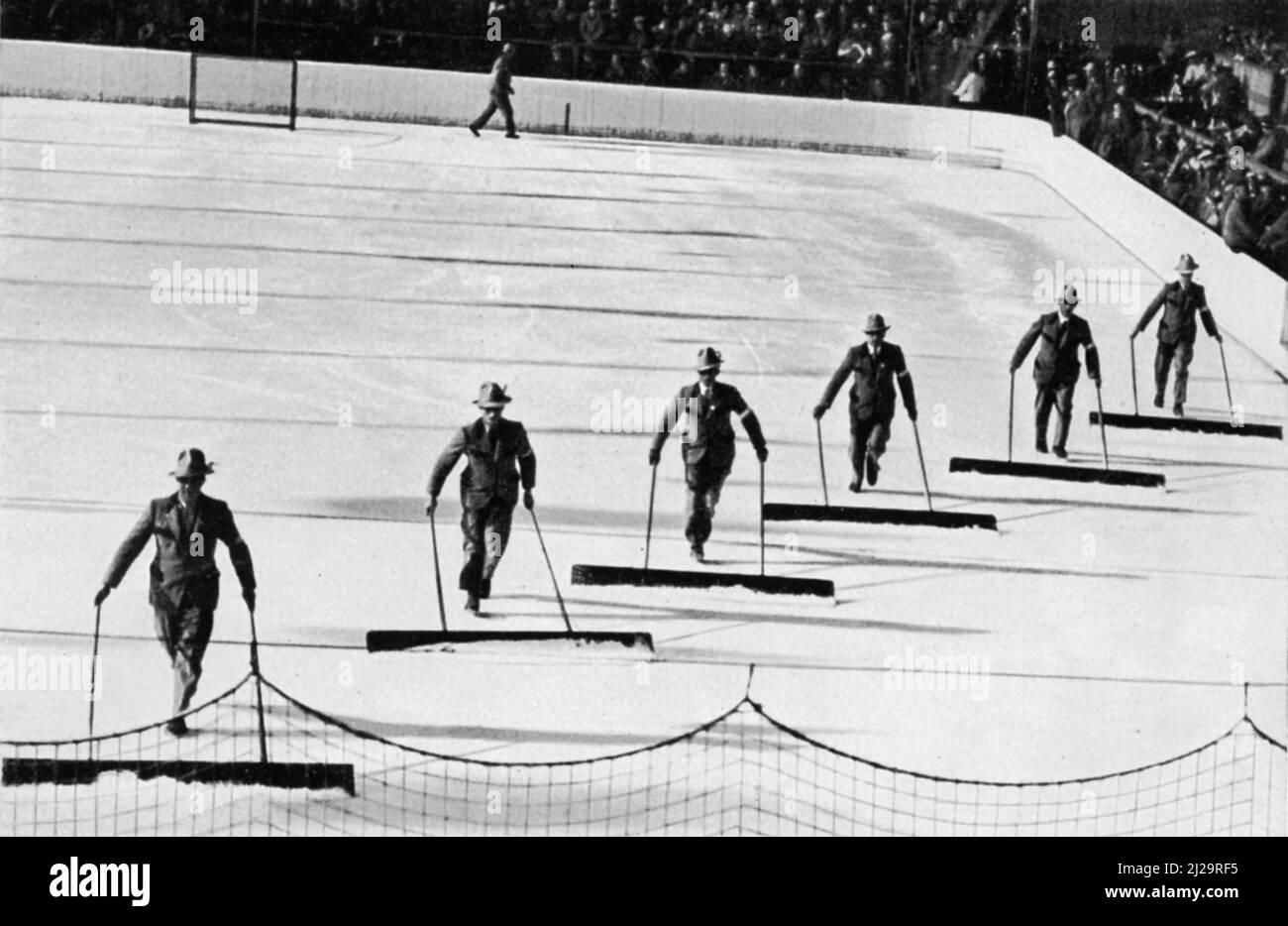 Eisstadion, die St. Petersburger Schlittenfahrt, oder die lustigen Schneeskater in der Werdenfelser Tracht reinigen die Eisfläche der Stockfoto