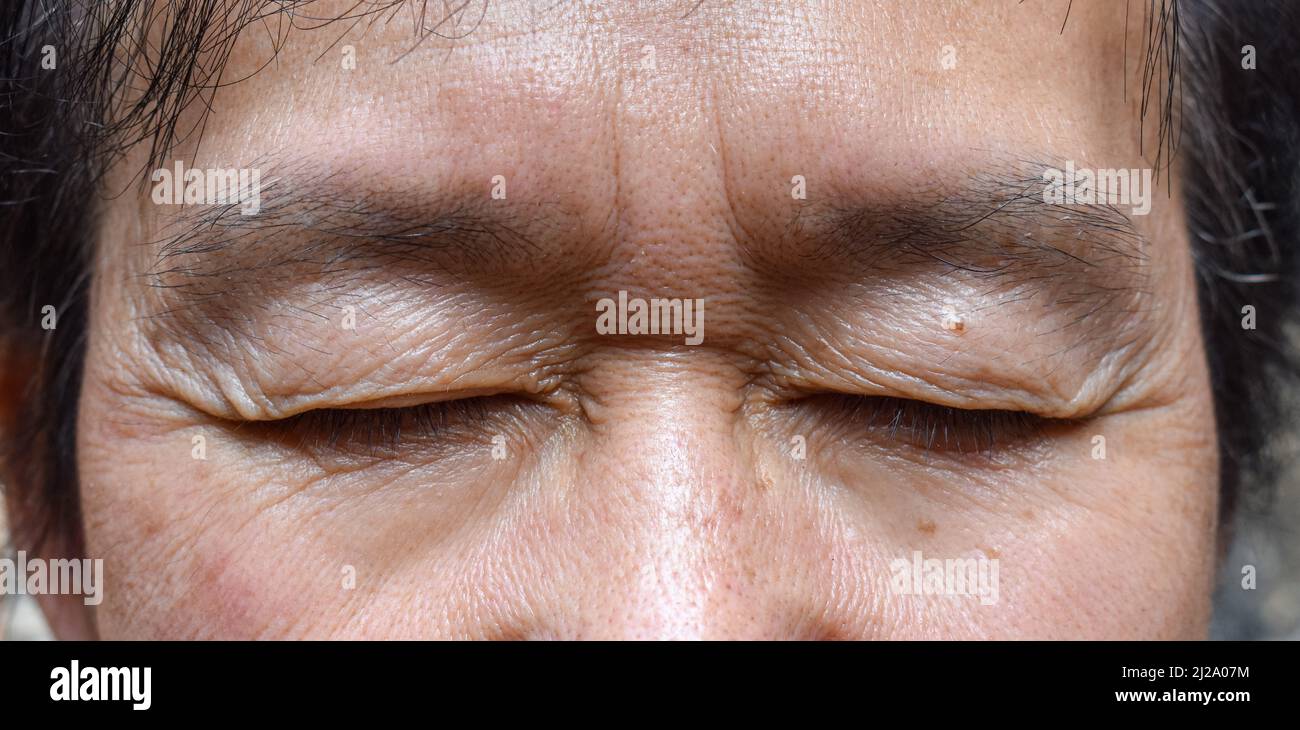 Falten um das geschlossene Auge des älteren asiatischen Mannes. Nahaufnahme. Stockfoto