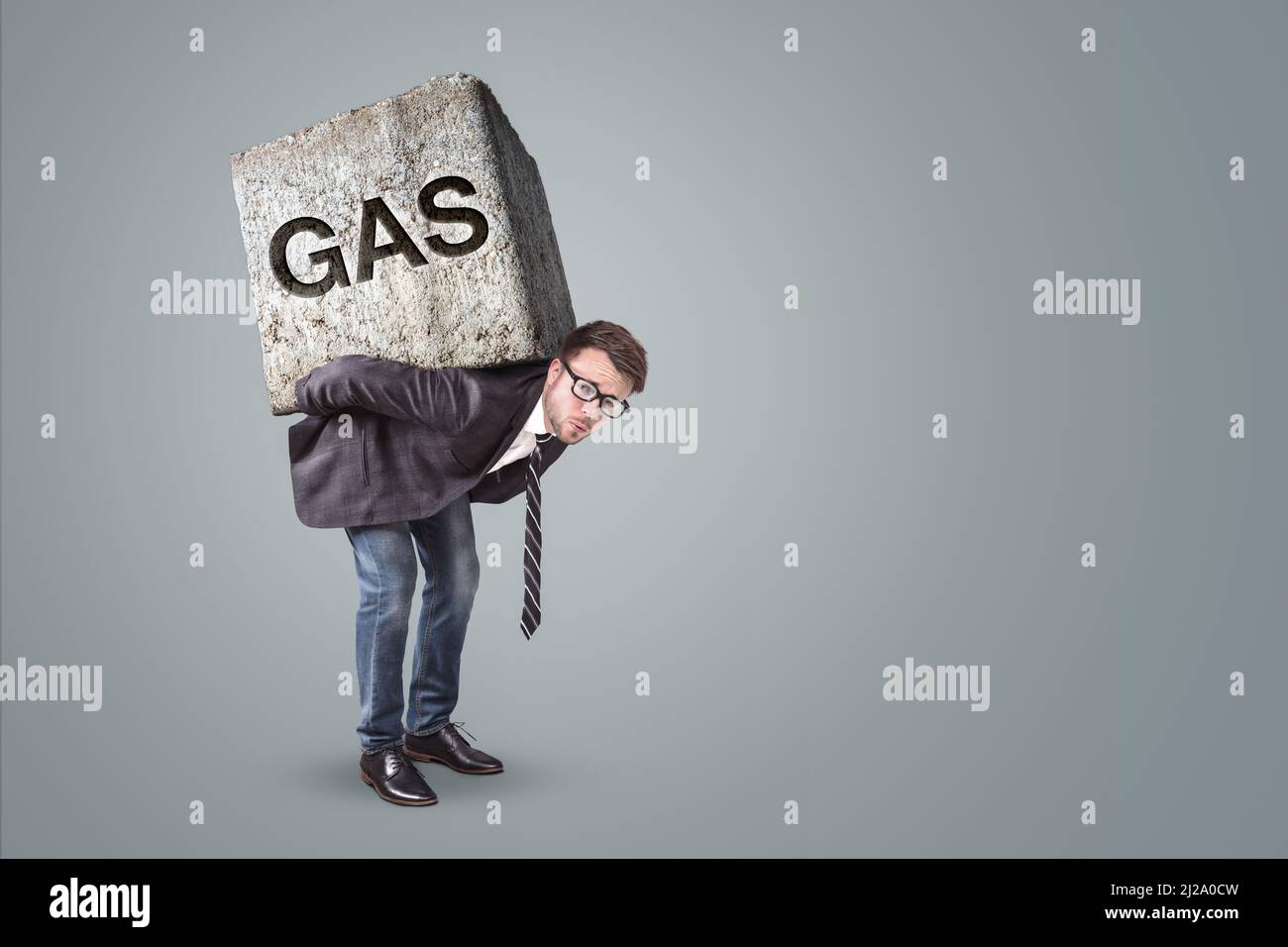 Person, die von einem schweren Stein mit dem Wort GAS darauf belastet ist Stockfoto