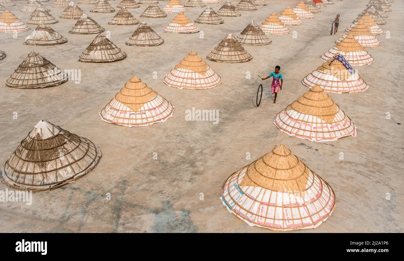 Brahmanbaria, Chittagong, Bangladesch. 31. März 2022. Kinder laufen und spielen zwischen Hunderten traditioneller Reismühlen aus Bambus.nach dem Kochen wird das Getreide von Arbeitern in Haufen gefegt und bis zu acht Stunden lang in Brahmanbaria, Bangladesch, getrocknet. Die Reismühlenarbeiter begannen ihre Arbeit von sehr früh morgens von 5 bis 2pm Uhr täglich. Nach der Mittagspause spielen die Kinder der Arbeiter ihre Nachmittagsspiele mit Freunden in diesem Reismühlenfeld. (Bild: © Mustasinur Rahman Alvi/ZUMA Press Wire) Bild: ZUMA Press, Inc./Alamy Live News Stockfoto