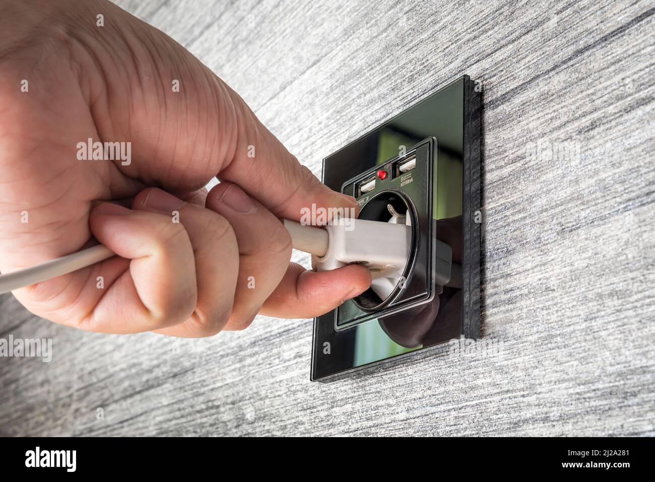 Hand Putting Plug in Electricity Modern Socket. Anschluss an die Stromversorgung an der Wand aus einer Steckdose. Stockfoto