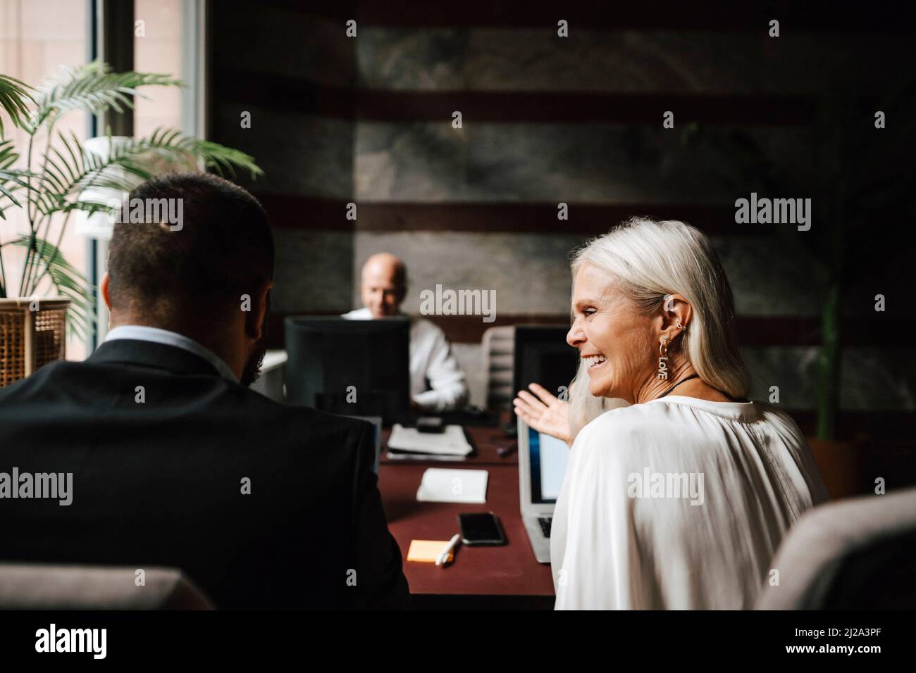 Fröhliche weibliche Finanzberaterin, die mit einem männlichen Kollegen in der Anwaltskanzlei diskutiert Stockfoto
