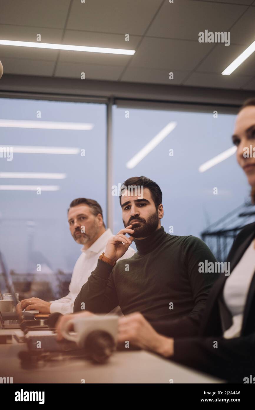 Ehrgeiziger Geschäftsmann inmitten von Kollegen und Kolleginnen, die spät im Amt arbeiten Stockfoto