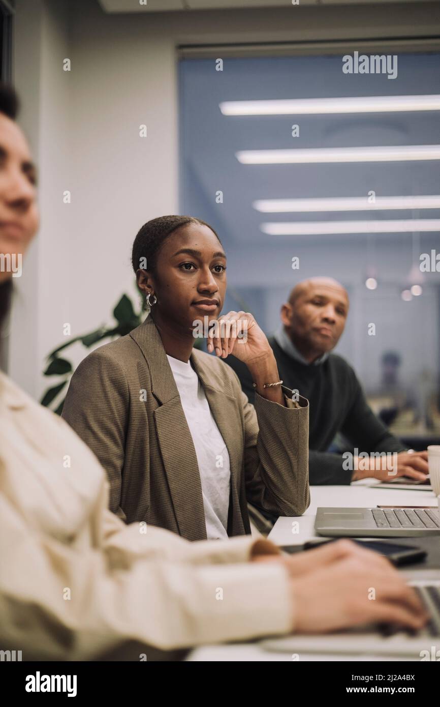 Geschäftsfrau mit männlichen und weiblichen Kollegen, die am Arbeitsplatz Überstunden machen Stockfoto