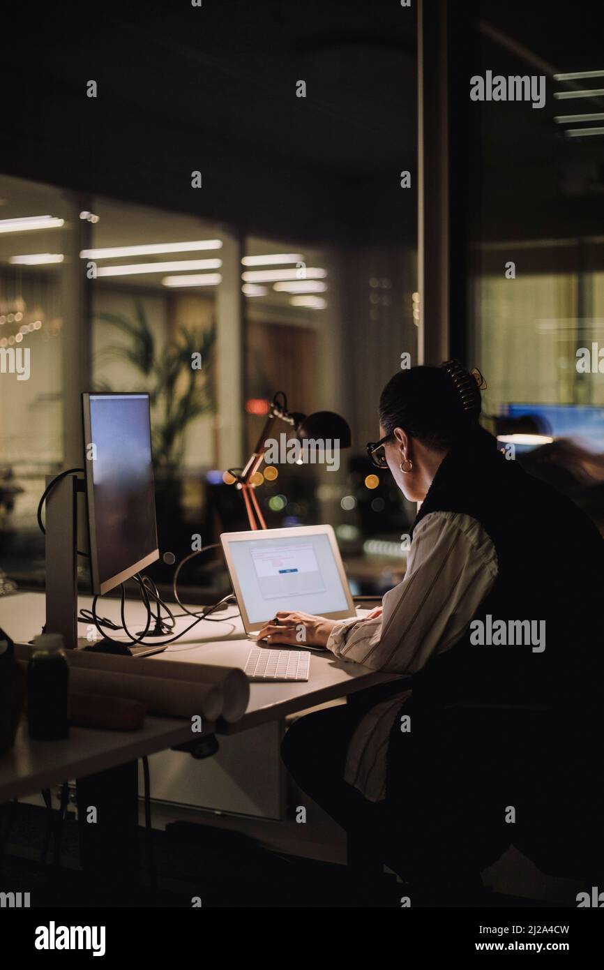 Geschäftsfrau, die nachts im Büro mit einem Laptop arbeitet Stockfoto