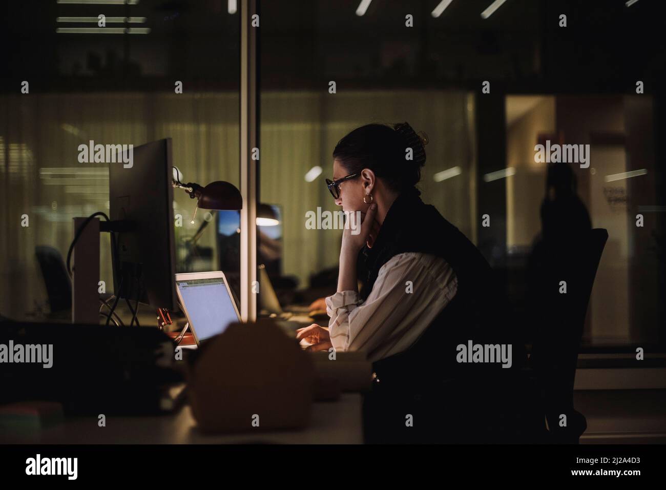 Ambitionierte Geschäftsfrau, die spät abends im Büro mit einem Laptop arbeitet Stockfoto