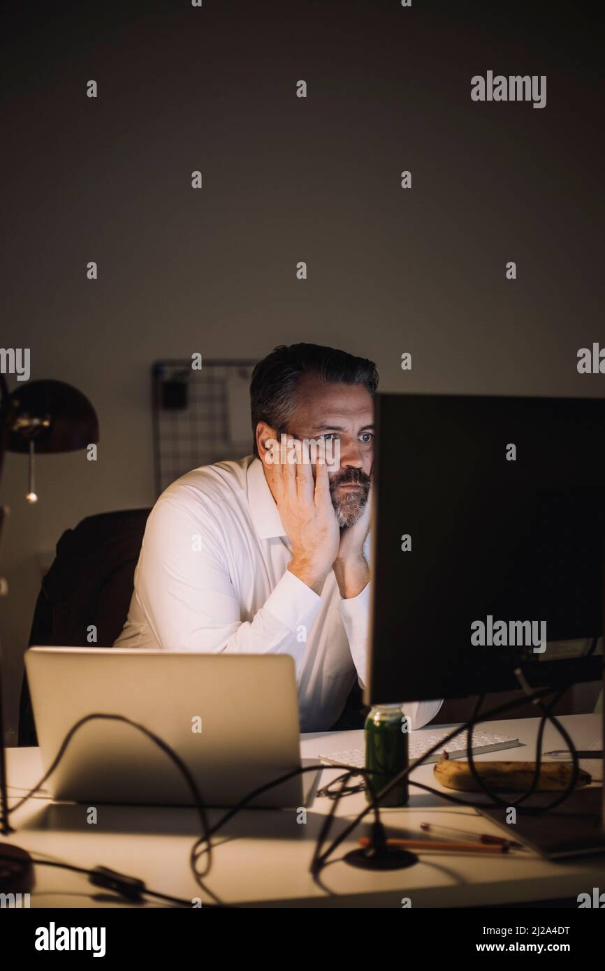 Ehrgeiziger Geschäftsmann, der in letzter Minute am Arbeitsplatz am Computer arbeitet Stockfoto