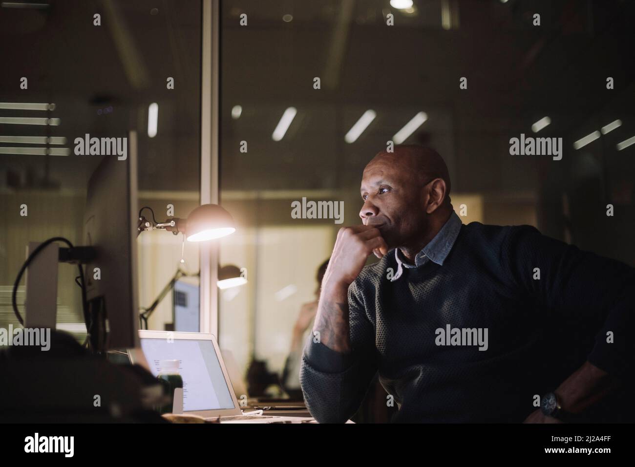 Ambitionierter Arbeiter, der am Arbeitsplatz Überstunden am Computer arbeitet Stockfoto