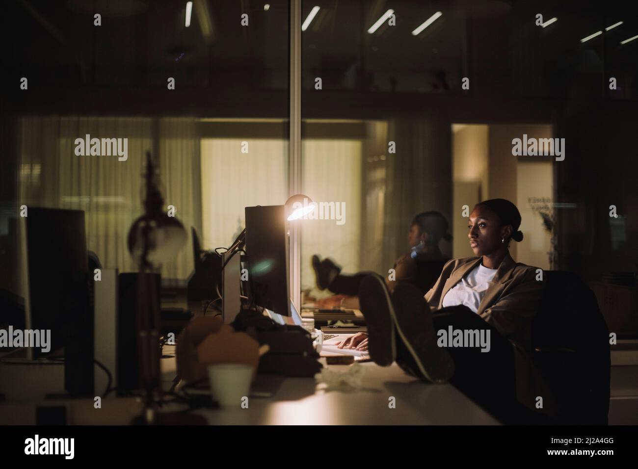Geschäftsfrau mit mittlerem Erwachsenenalter, die während der Überstunden im Büro einen Laptop verwendet Stockfoto
