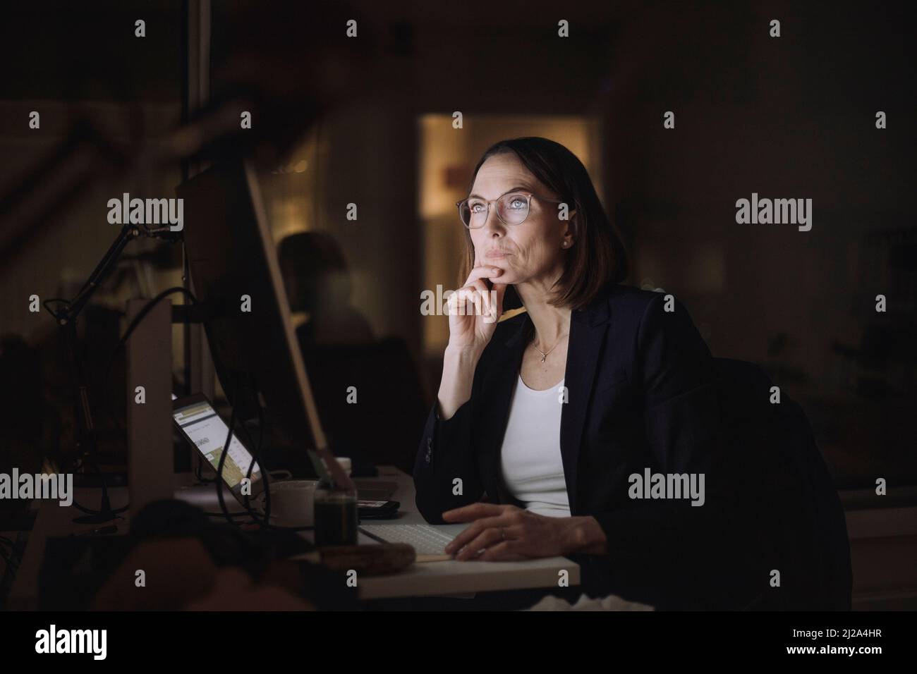 Ambitionierte Geschäftsfrau, die nachts am Computer im Büro Überstunden gemacht hat Stockfoto