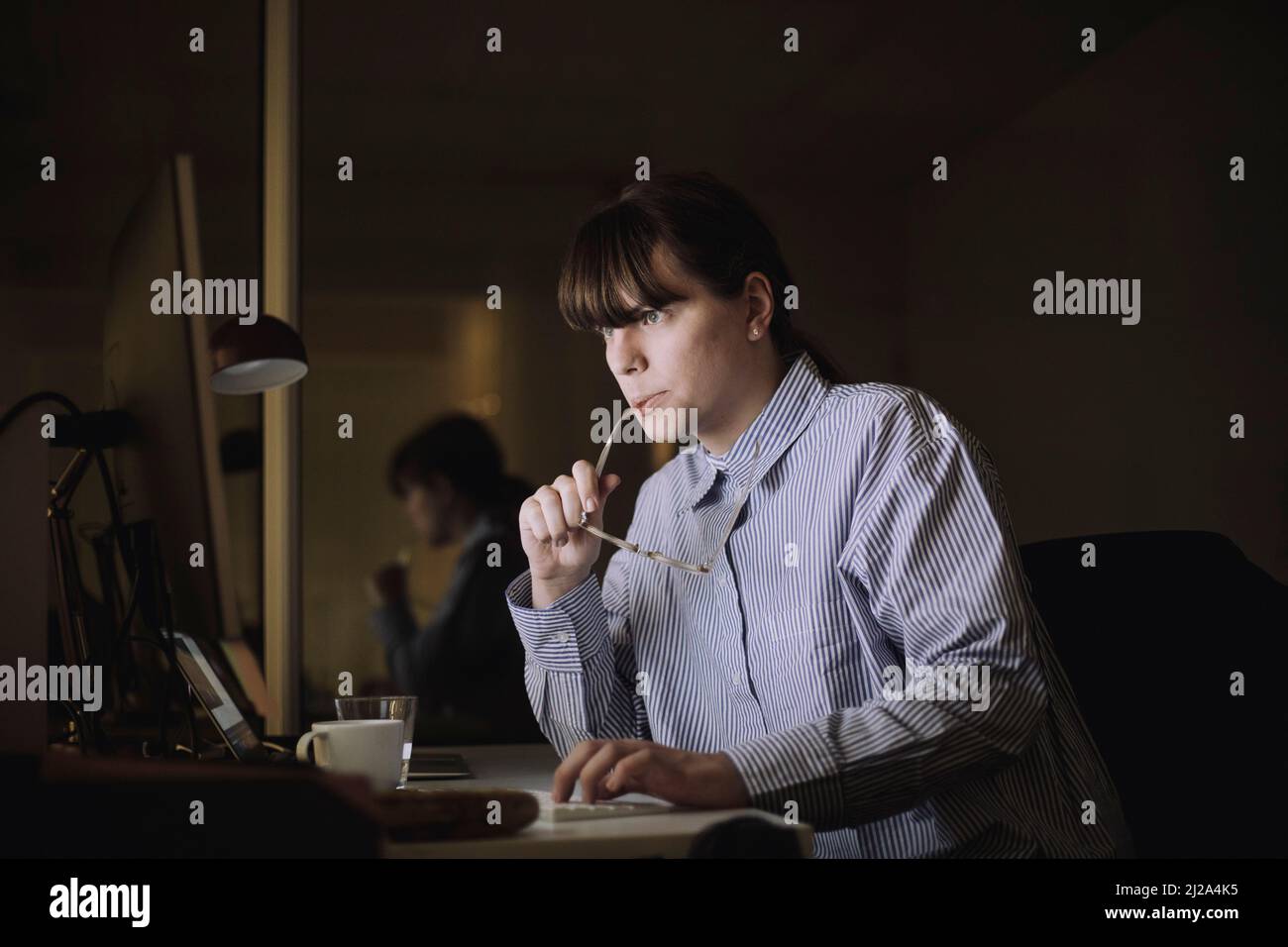 Junge Geschäftsfrau, die am Arbeitsplatz am Computer arbeitet Stockfoto