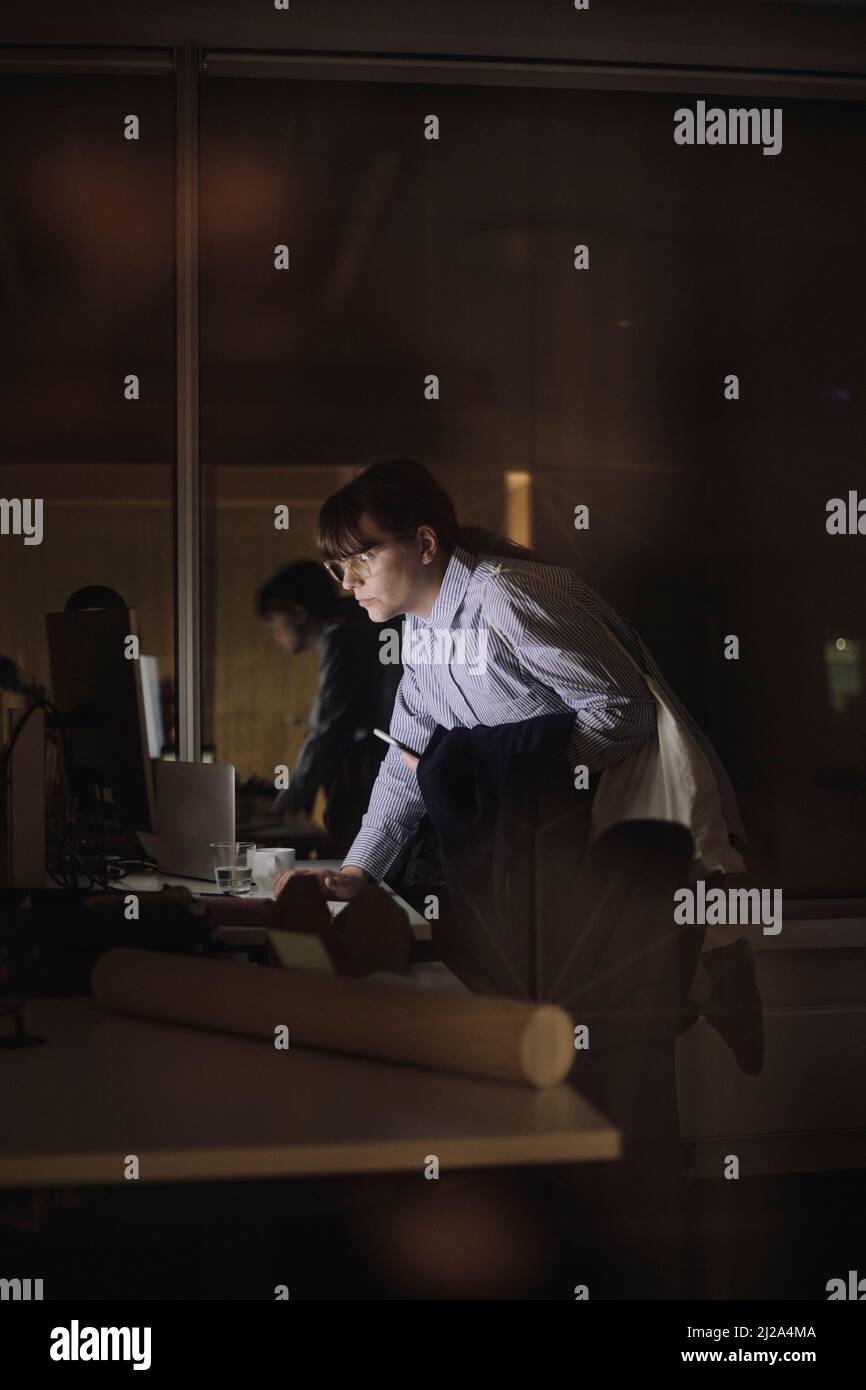 Junge Geschäftsfrau, die in letzter Minute am Arbeitsplatz am Computer arbeitet Stockfoto