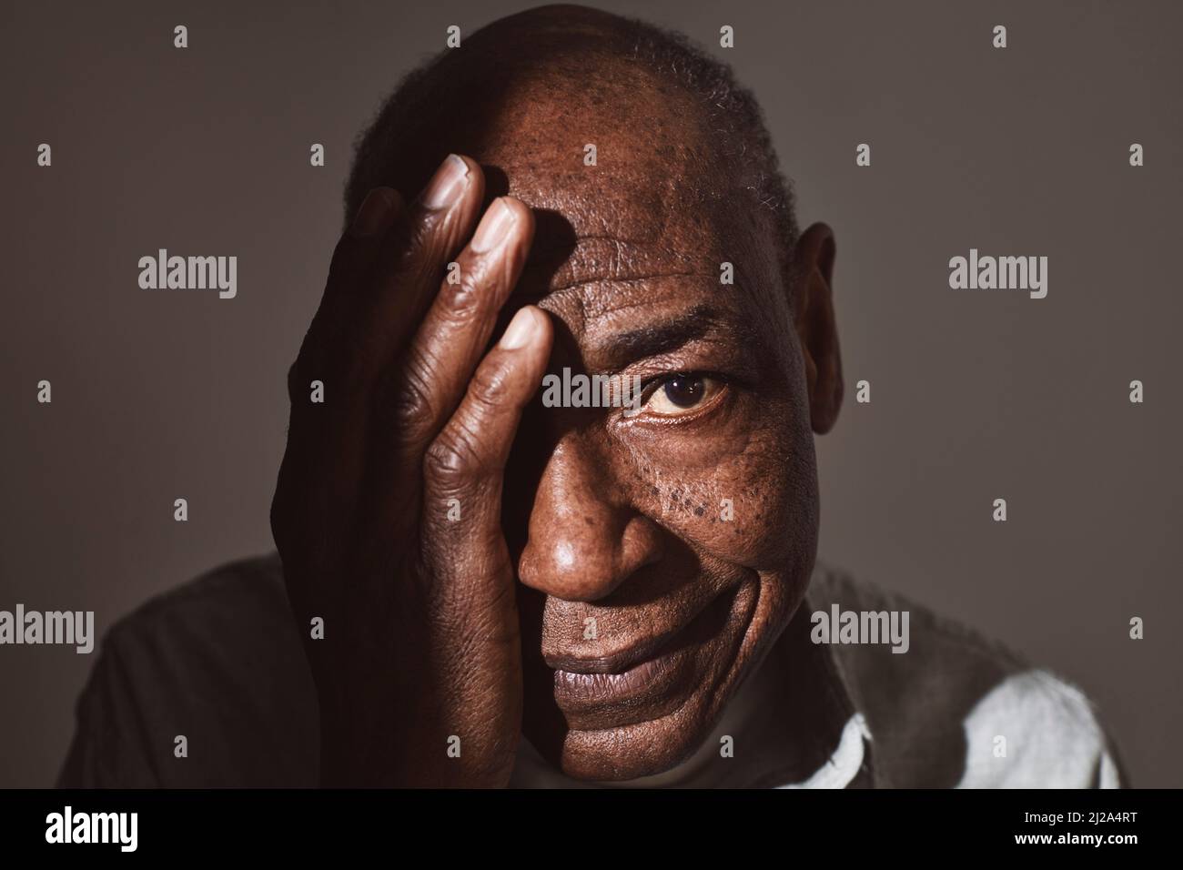 Älterer Mann, der das Auge mit der Hand auf weißem Hintergrund bedeckt Stockfoto