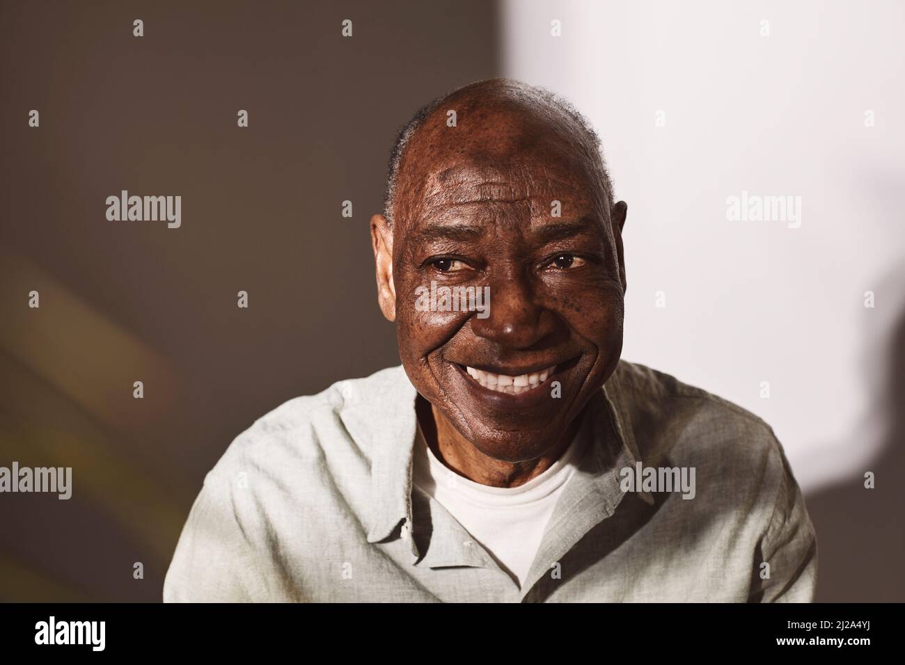 Lächelnder älterer Mann, der vor weißem Hintergrund wegschaut Stockfoto